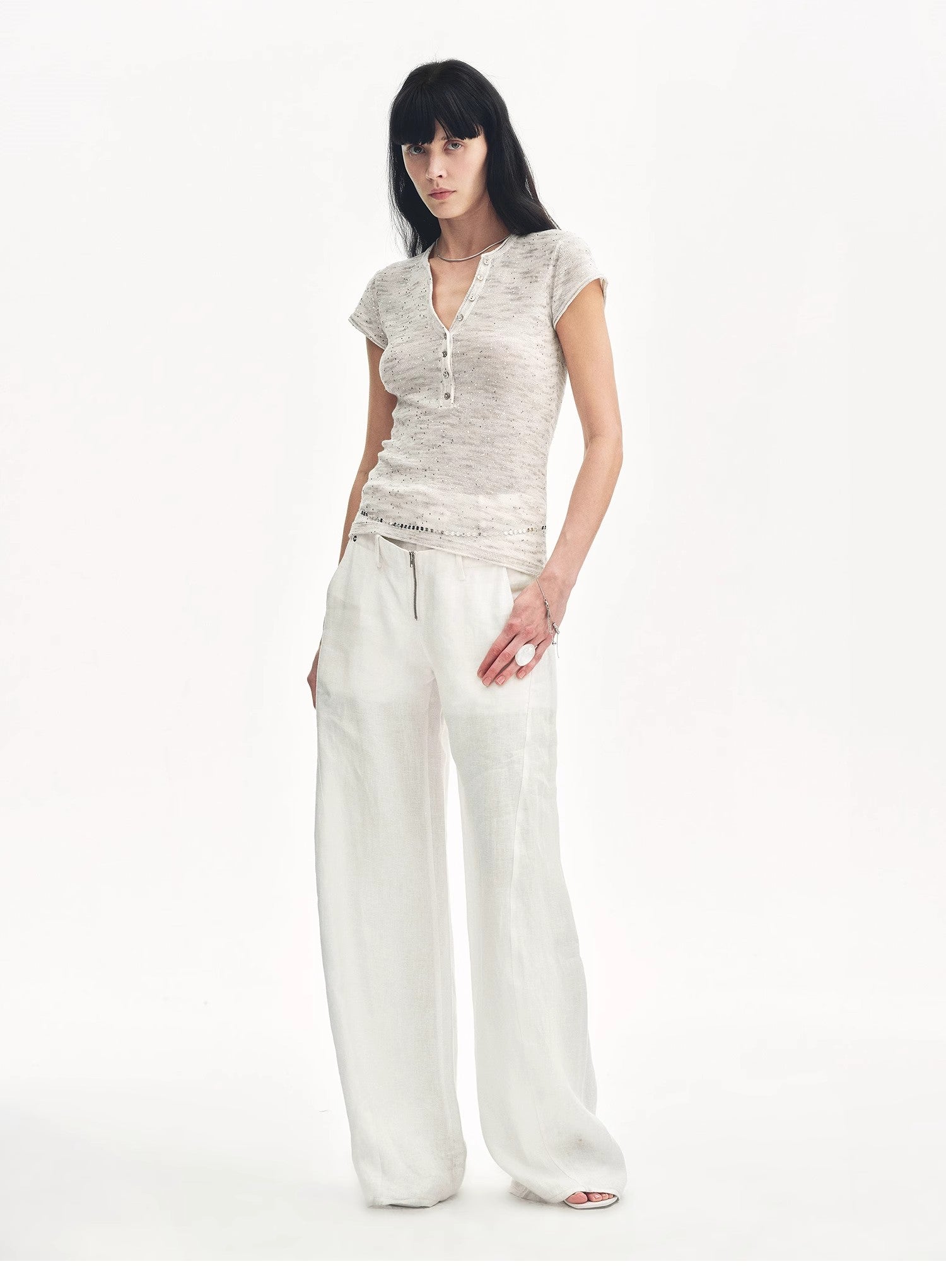 Woman wearing a light-colored top and wide-leg pants on a white background